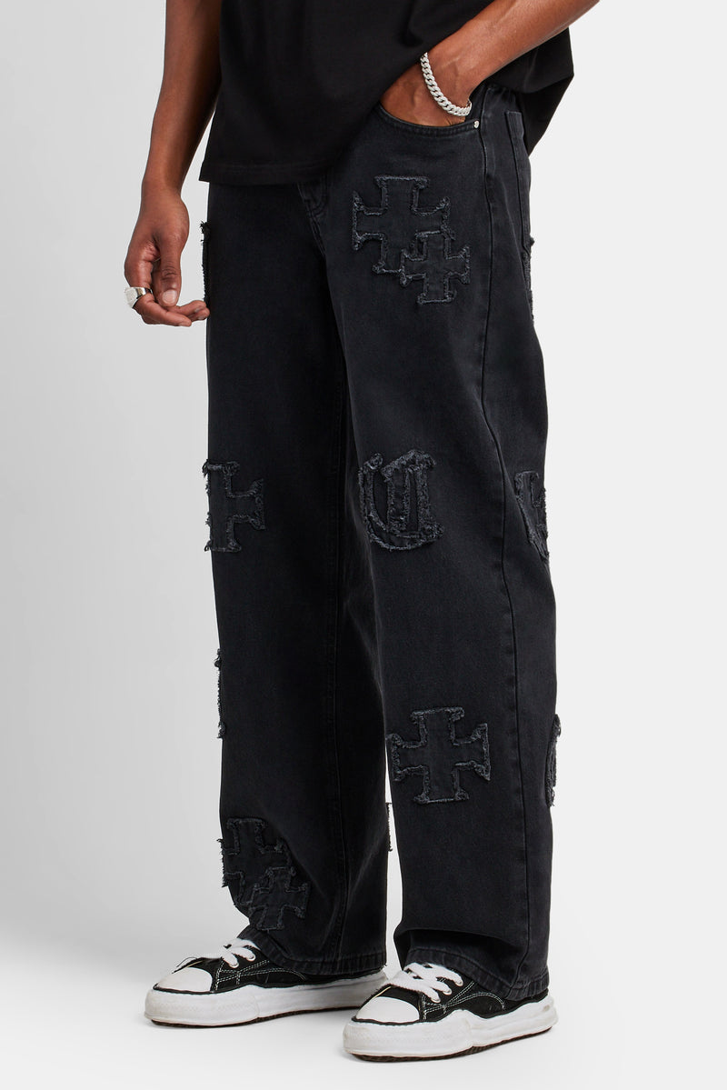 Male model wearing the baggy raw edge applique jeans in washed black